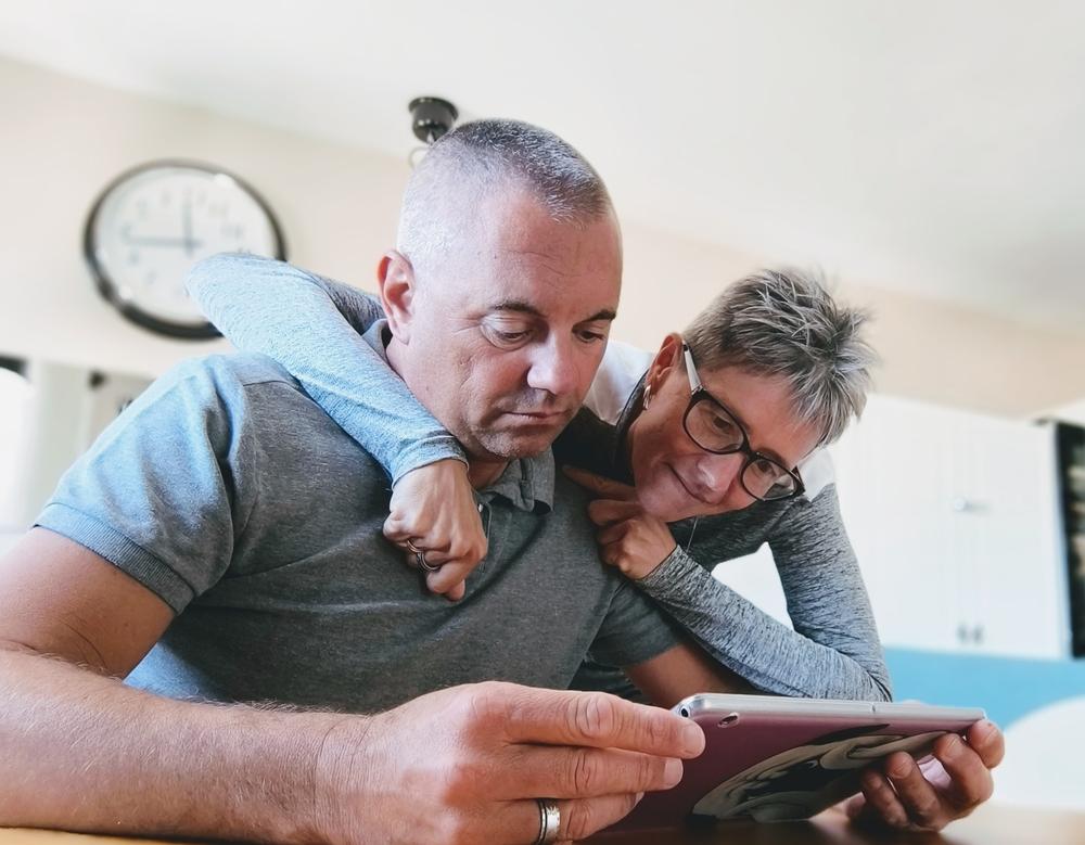 Man houdt een tablet vast en vrouw kijkt mee over zijn schouder